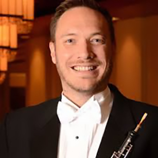 Dr. Andrew Parker in a tux, with a big smile, holding an oboe