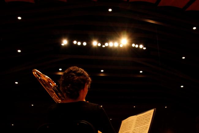view from backstage of a person playing trombone to a concert hall