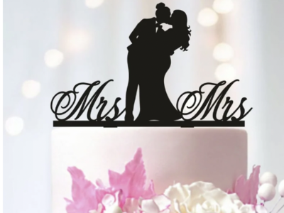 cake topper depicting a couple kissing with the words "Mrs" and "Mrs" on either side.