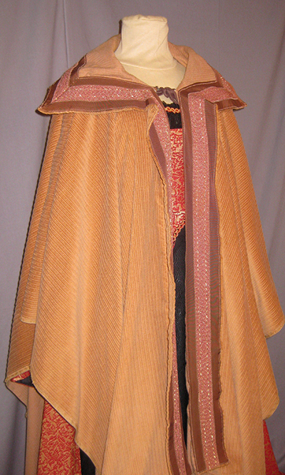 light orange shawl-style cape with wing collar and rose detail.