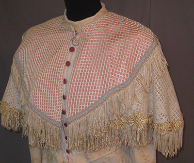 shoulder cape, buttoned down front, checked pattern, some fringe.