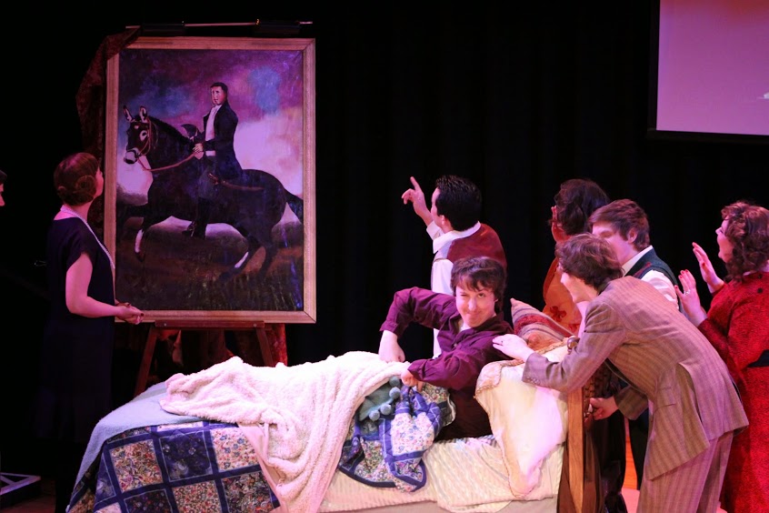 actors crowded around an actor in a bed. A large painting of person on horse nearby.