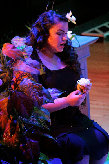 seated contemplative actor sings to a flower.
