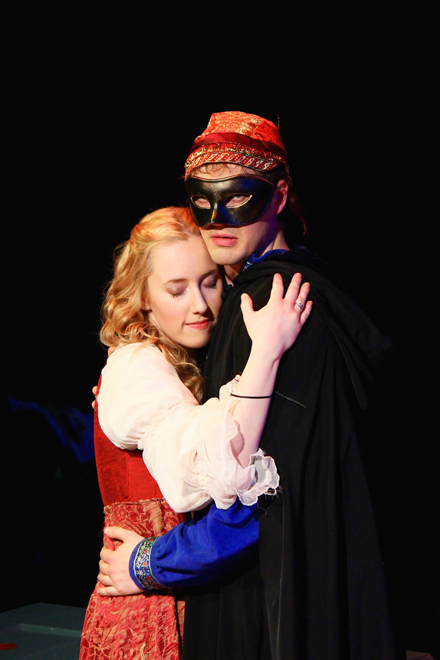actor in mask clutching woman in dress in romantic pose