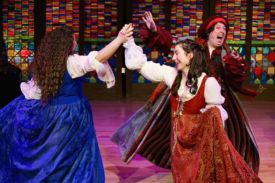 three opera singers in renaissance costumes engaged in a traditional dance
