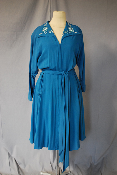 below-knee blue dress. Belted. Lapels with floral patern.