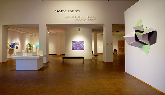 A gallery with several bays. Walls with paintings and sculptures.