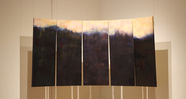 A set of five paintings in a series suspended from the ceiling.