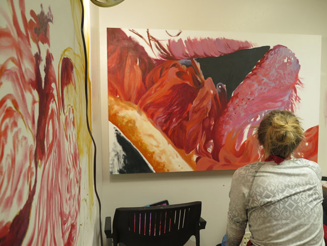 a painter with several large paintings. Red and pink.