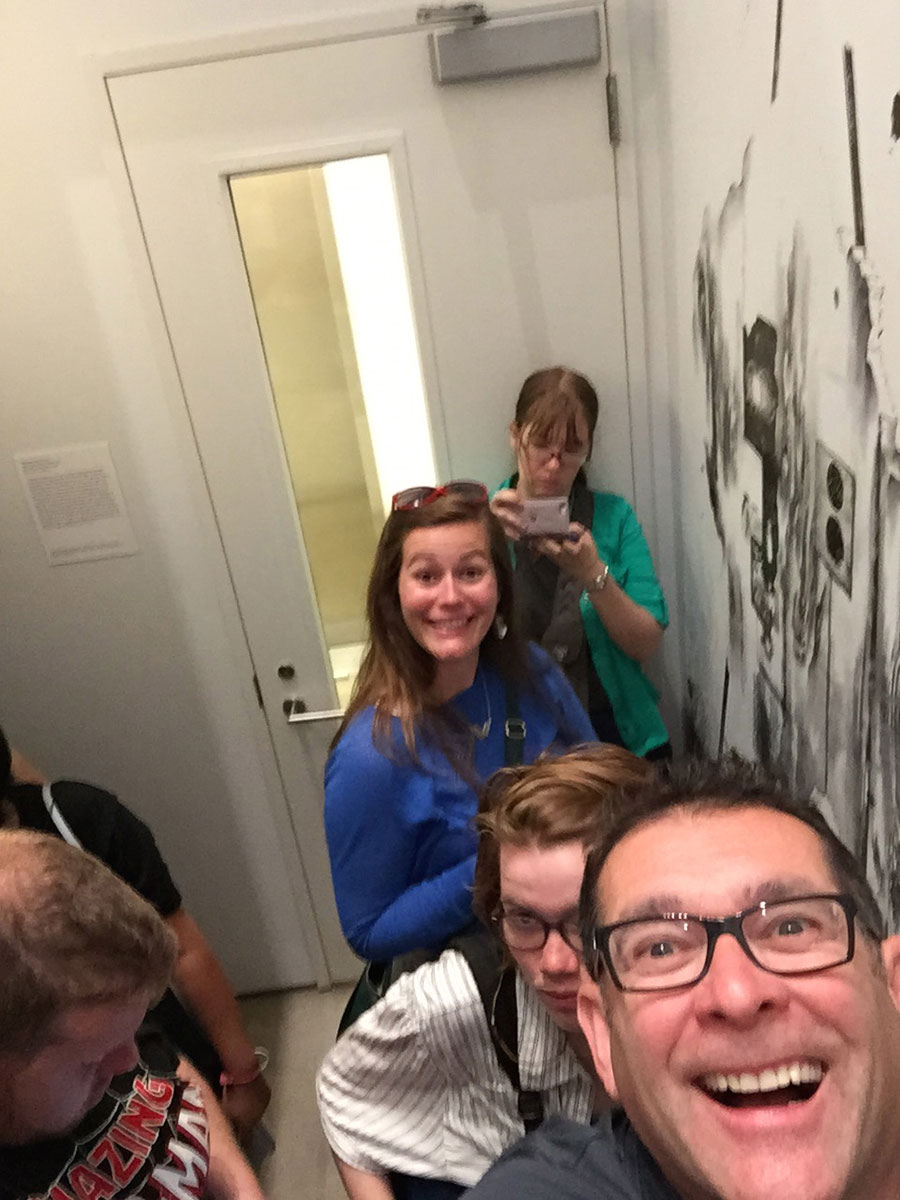 students and instructor Pierre Gour smiling broadly in a stairwell
