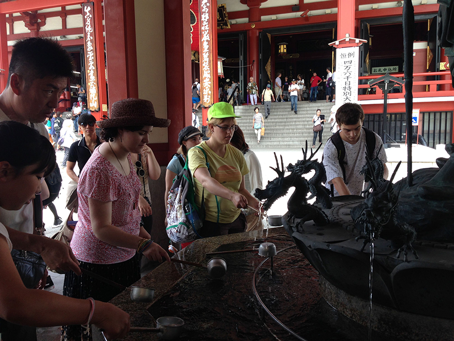 students wet sticks in a fountain with small dragon head spigots