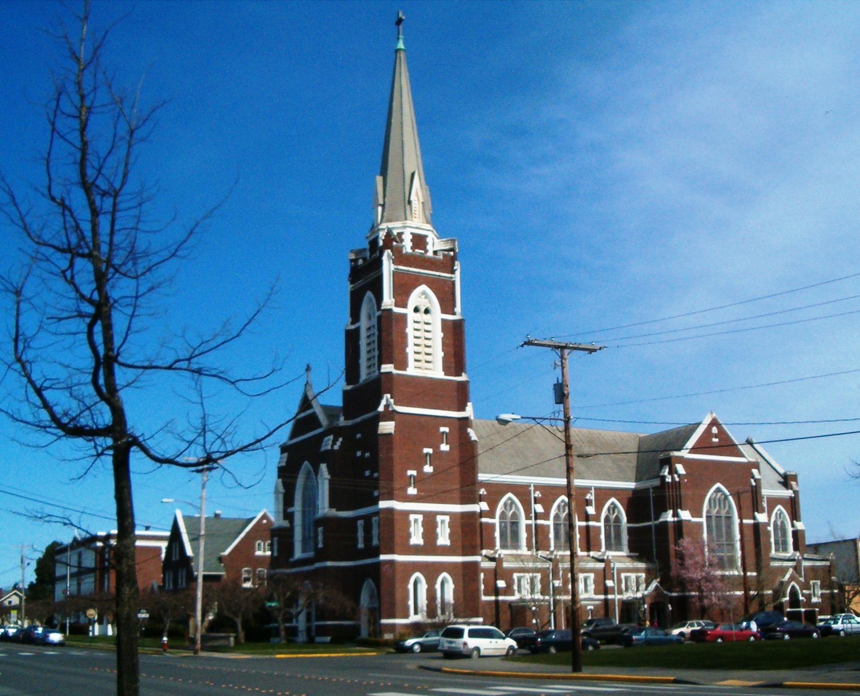 large brick church on a street corner with a pointy steeple