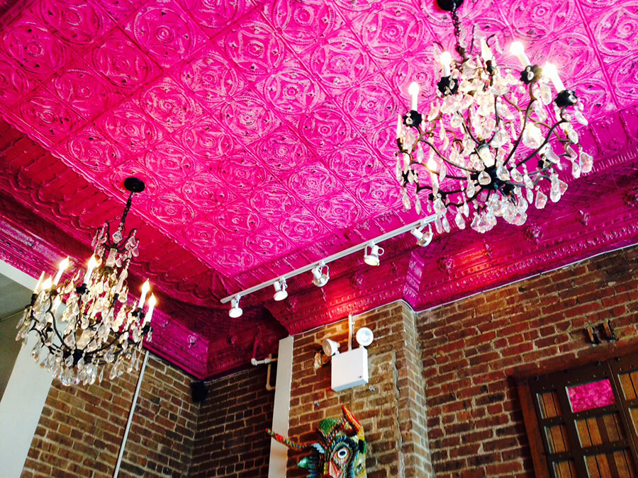 two chandeliers against a fuschia ceiling