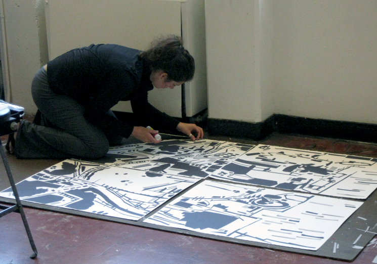 A student leans over a corner panel of a large four-panel ink drawing