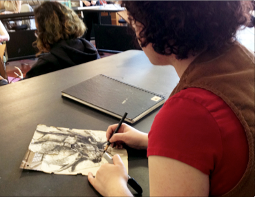 An over the shoulder view of a student working on a high contrast, detailed drawing