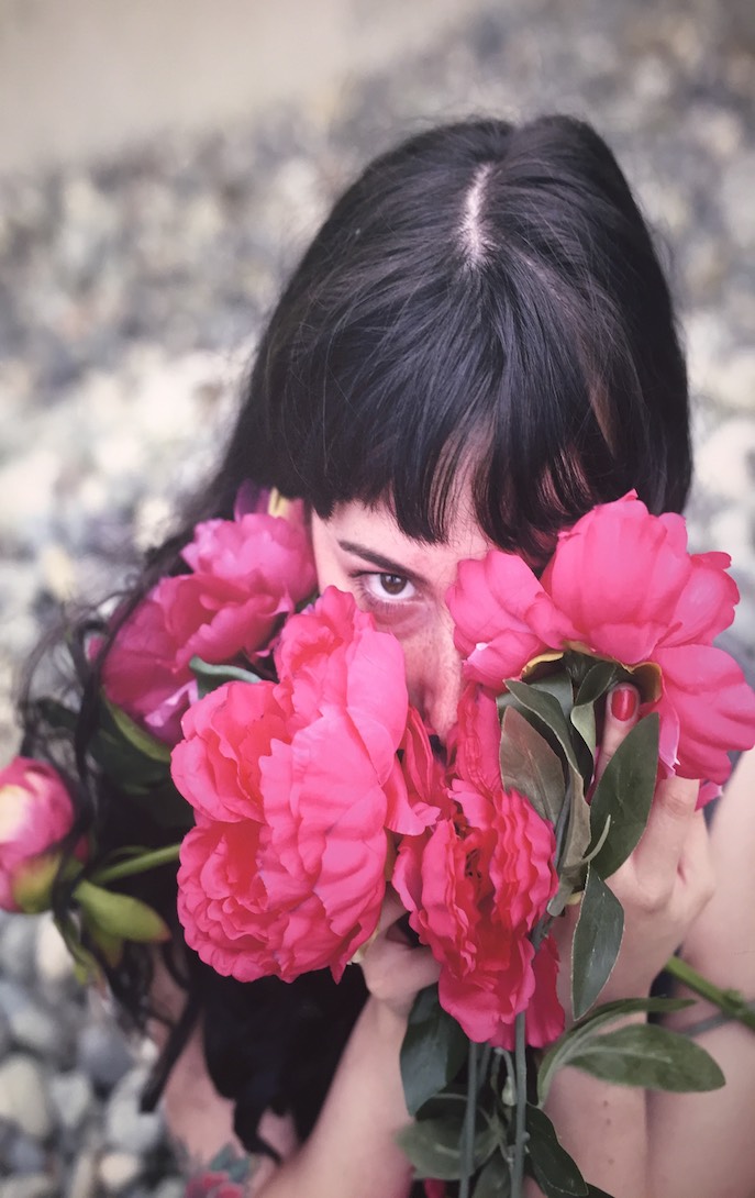 Person hiding their face in pink flowers