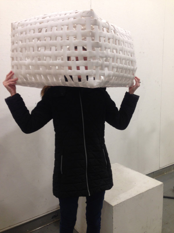 A person wearing a basket-woven box around their head