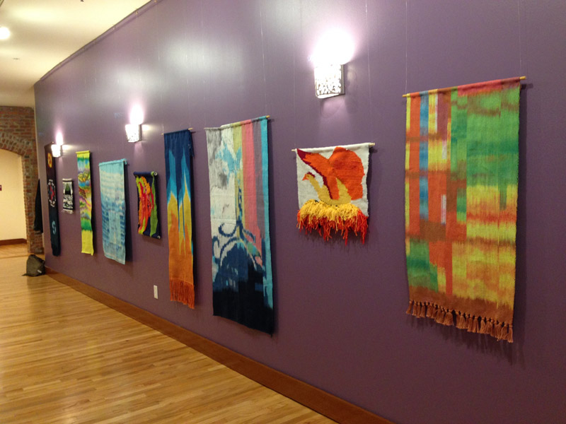 Series of fiber art displayed along a wall