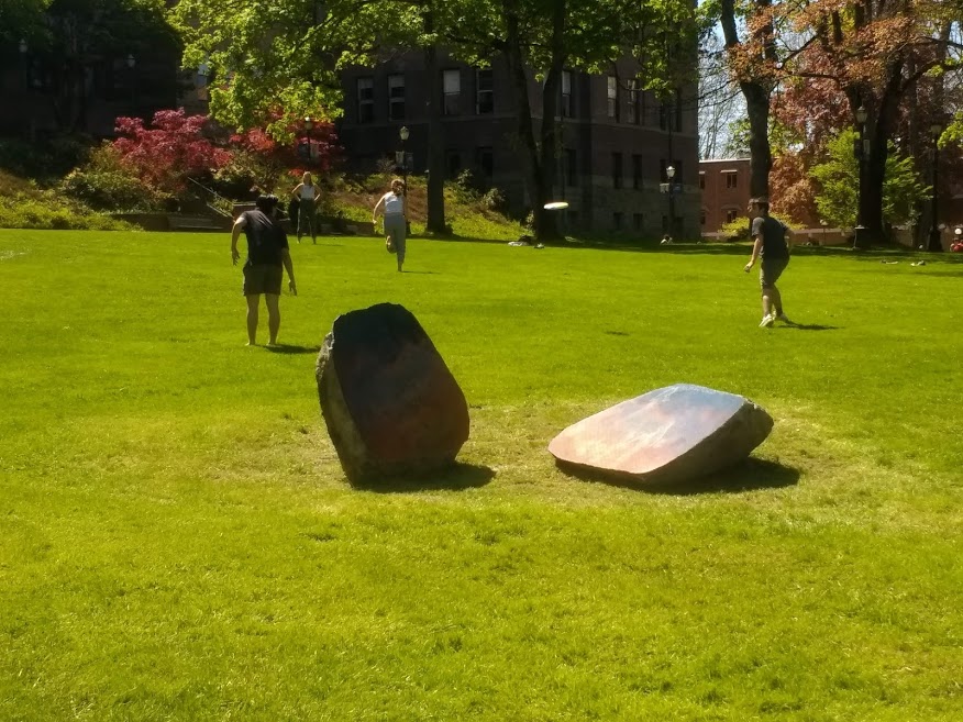 Students playing frisbee near a sculpture at WWU