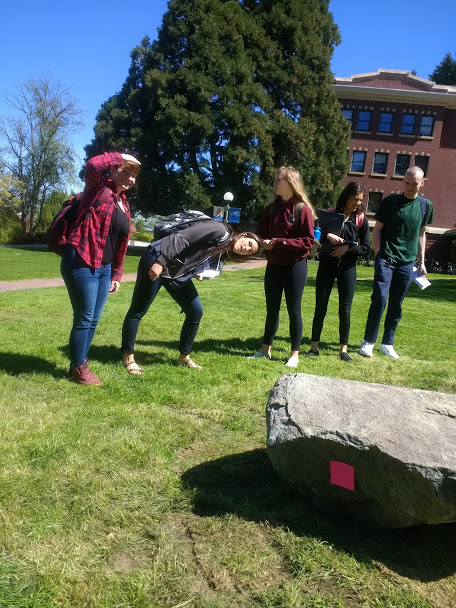 Students peering closely at a stone sculpture at Western Washington Universtiy