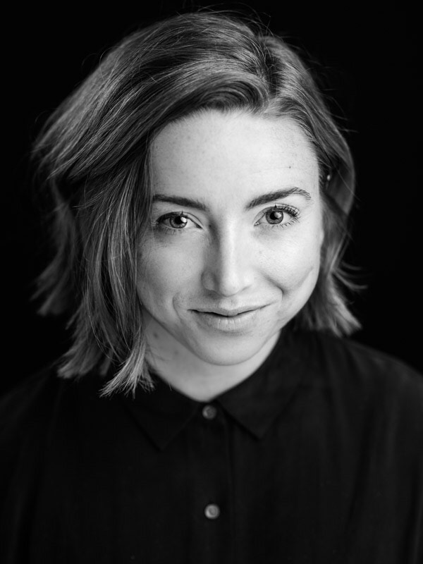 Portrait of a woman with short hair, bright eyes and a subtle open smile looking slightly up at the camera.