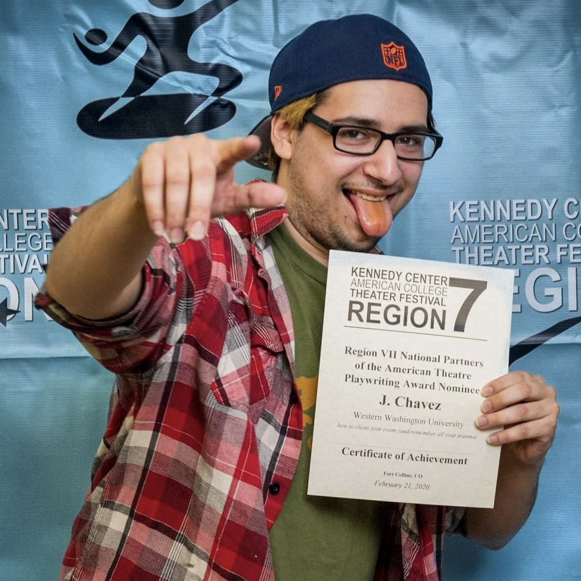 j. chavez in casual attire pointing, sticking out their tongue with a smile, holding a KCACTF certificate of achievement