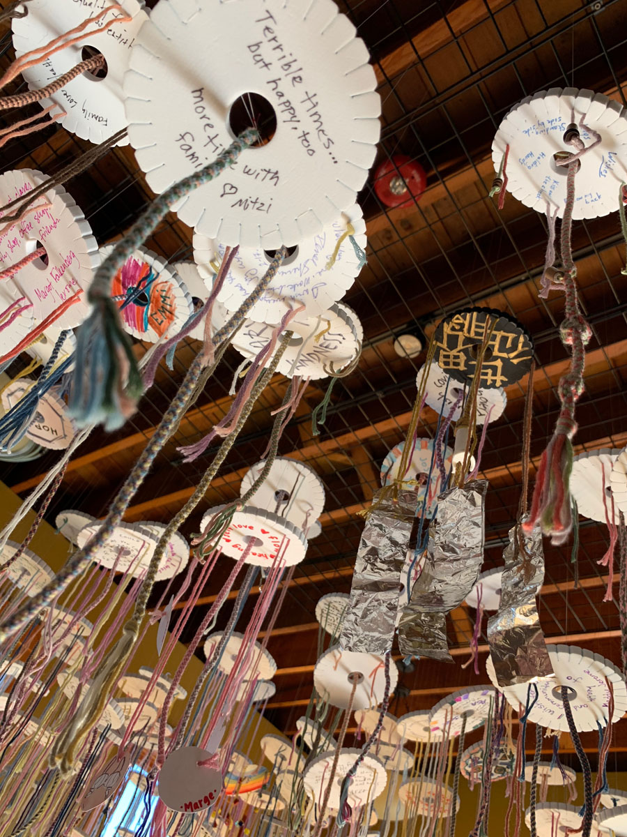many paper discs adorned with string and colorful markings suspended from a ceiling
