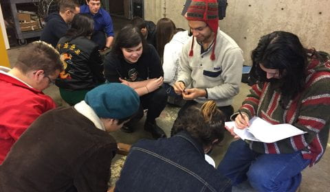 two groups of students sitting in circles, looking at shelled acorns and taking notes