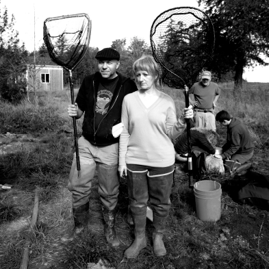black and white photo of people outside wearing long rubber boots holding fishing nets