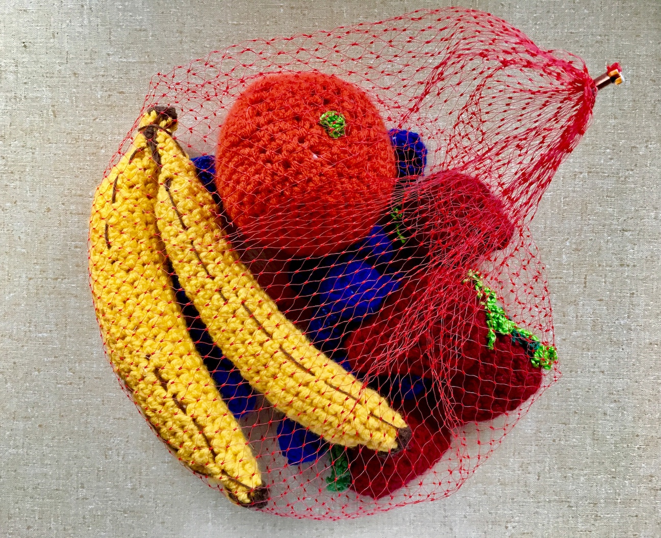 knitted 3D fruit in a bag made of netting