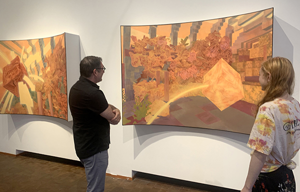 Two people looking at a large abstract painting displayed in a gallery. The painting is concave, rather than flat, against the wall. It depicts cubic and floral shapes.