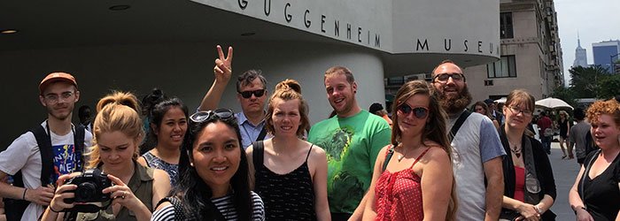 A group of students in front of the Guggenheim Museum, with a faculty member making the peace sign in the background