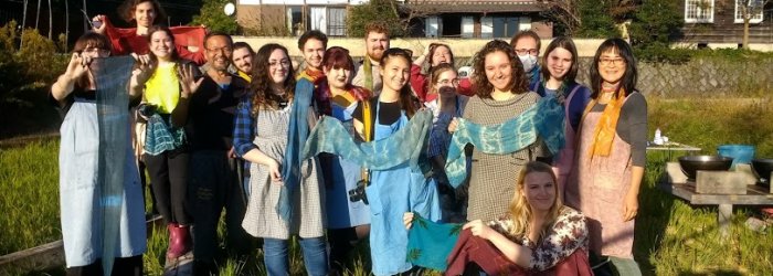 A group of students posing, each holding out a shibori dyed scarf