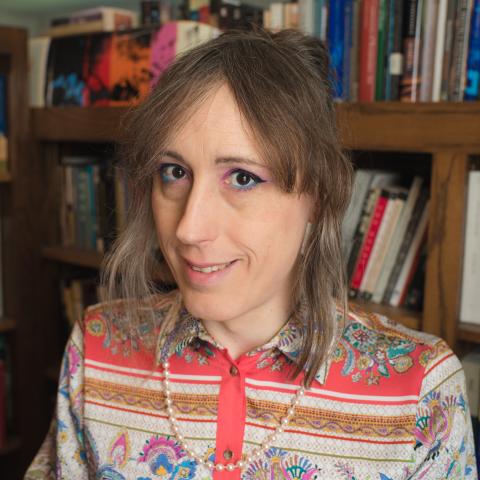person with light colored shoulder length hair in a colorful shirt