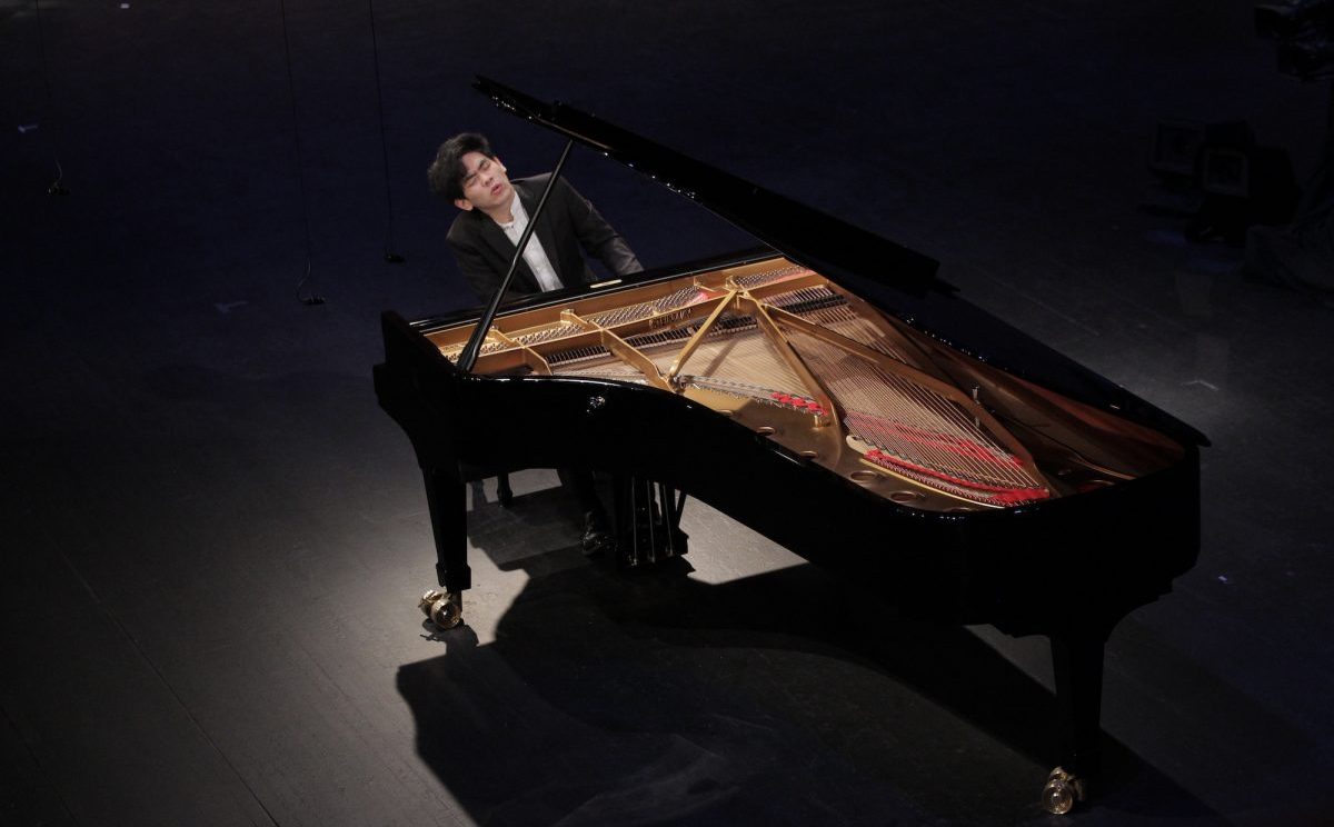 Daniel Hsu playing a steinway piano on stage, leaning back and to the side with eyes closed and mouth forming a soft "o"
