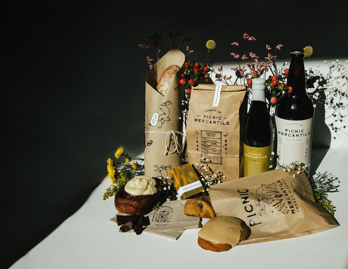 packaging for a company called Picnic features wine bottles, pastry bags, coffee bags on brown paper with twine