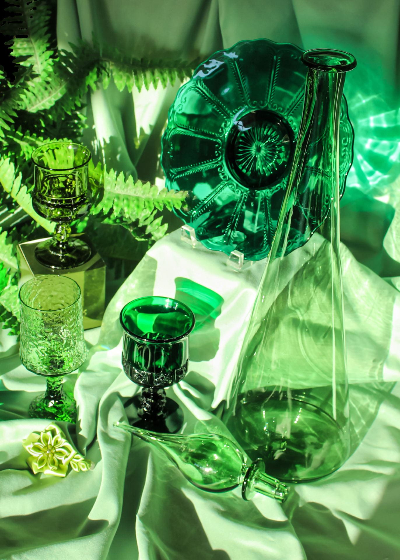 Arranged glass dishes and vases cast in bright green light