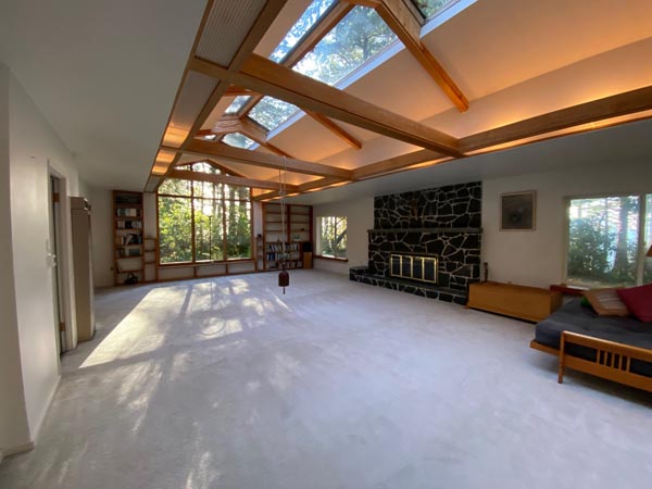 A spacious room with loads of skylights. There is a fireplace along the wall.