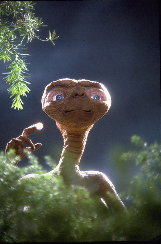 ET the extra-terrestrial peeks out from bushes with a glowing finger
