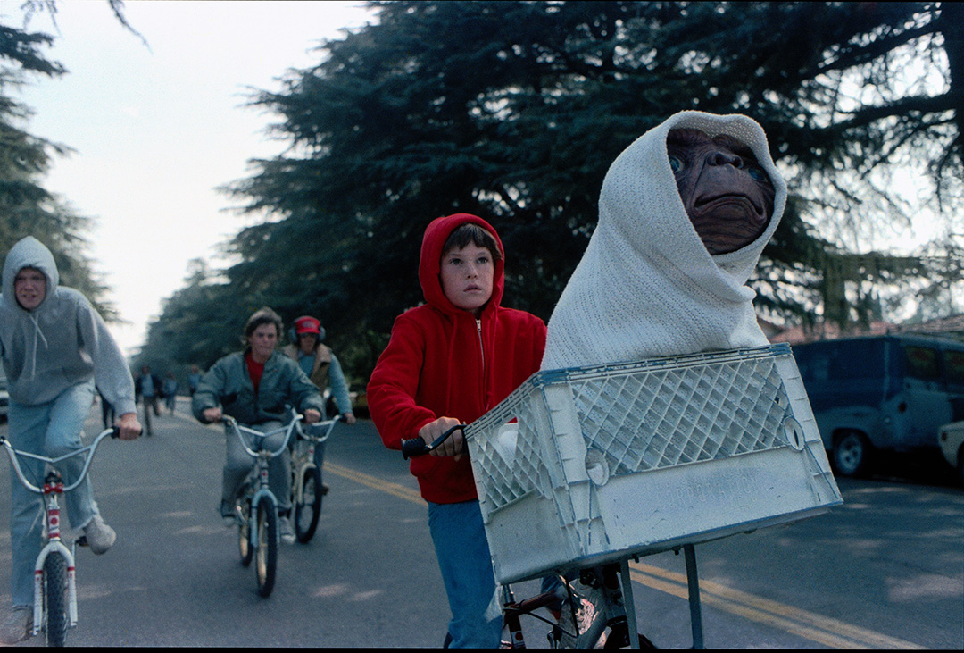boys on bicycles follow a boy on a bicycle with ET bundled in the front basket