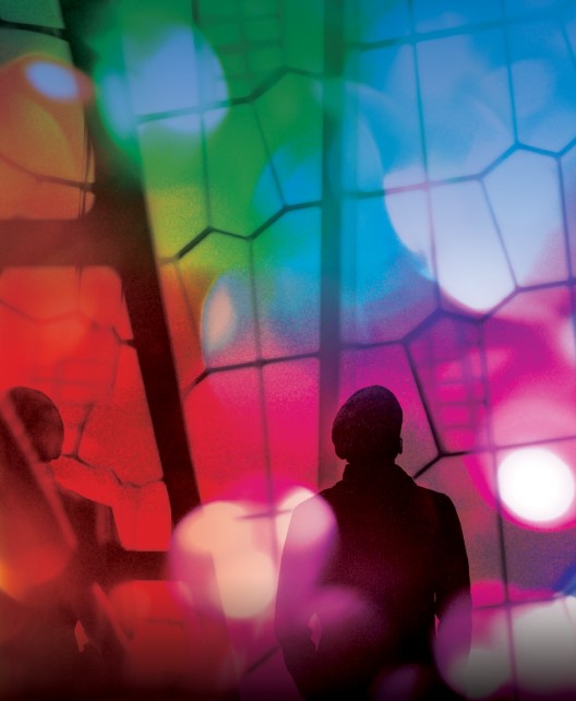 Silhouette of a person looking at a large, segmented window flooded with a rainbow of lights