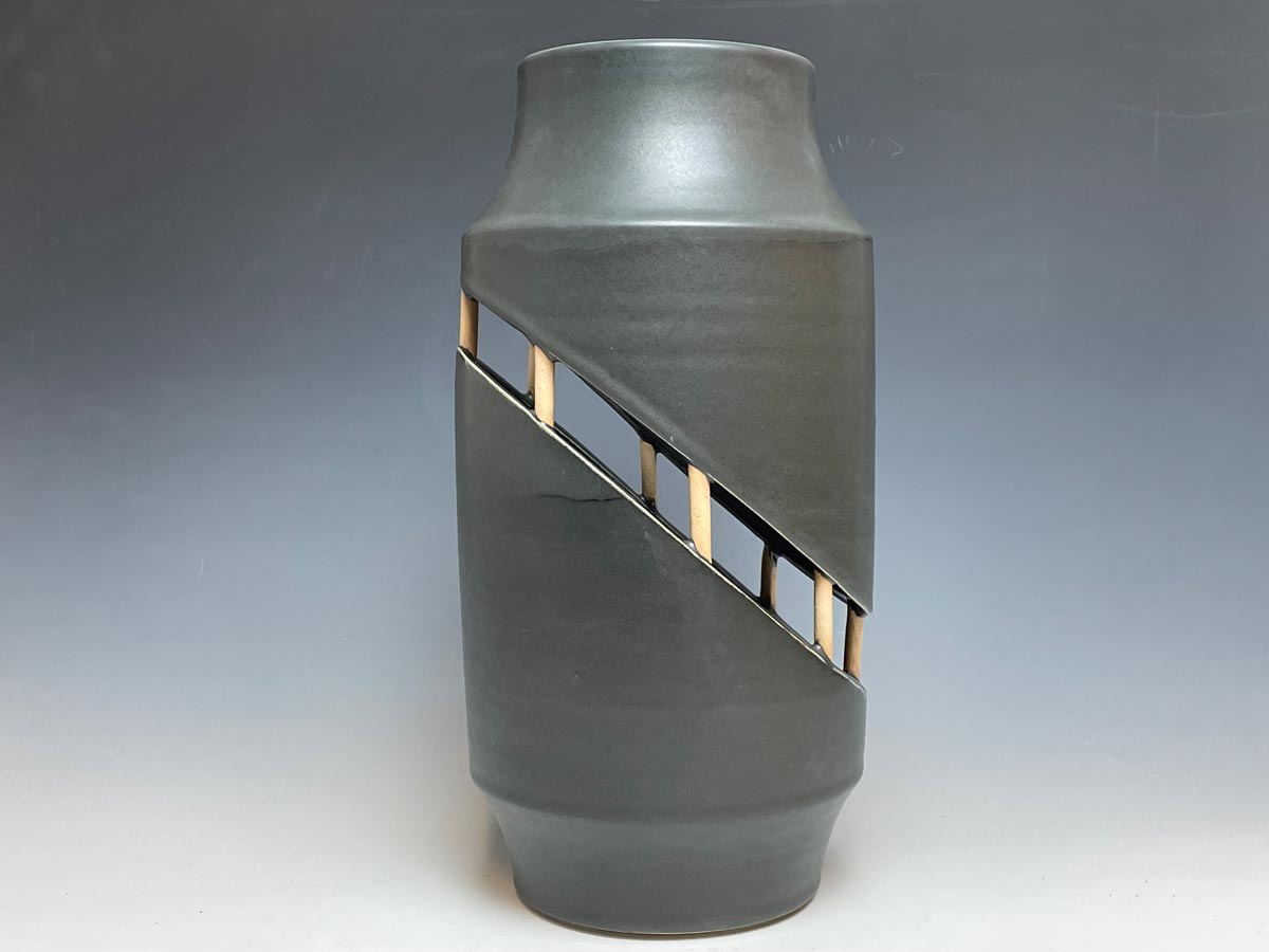 a ceramic urn that is fractured in a diagonal section then reattached to itself with small round supports