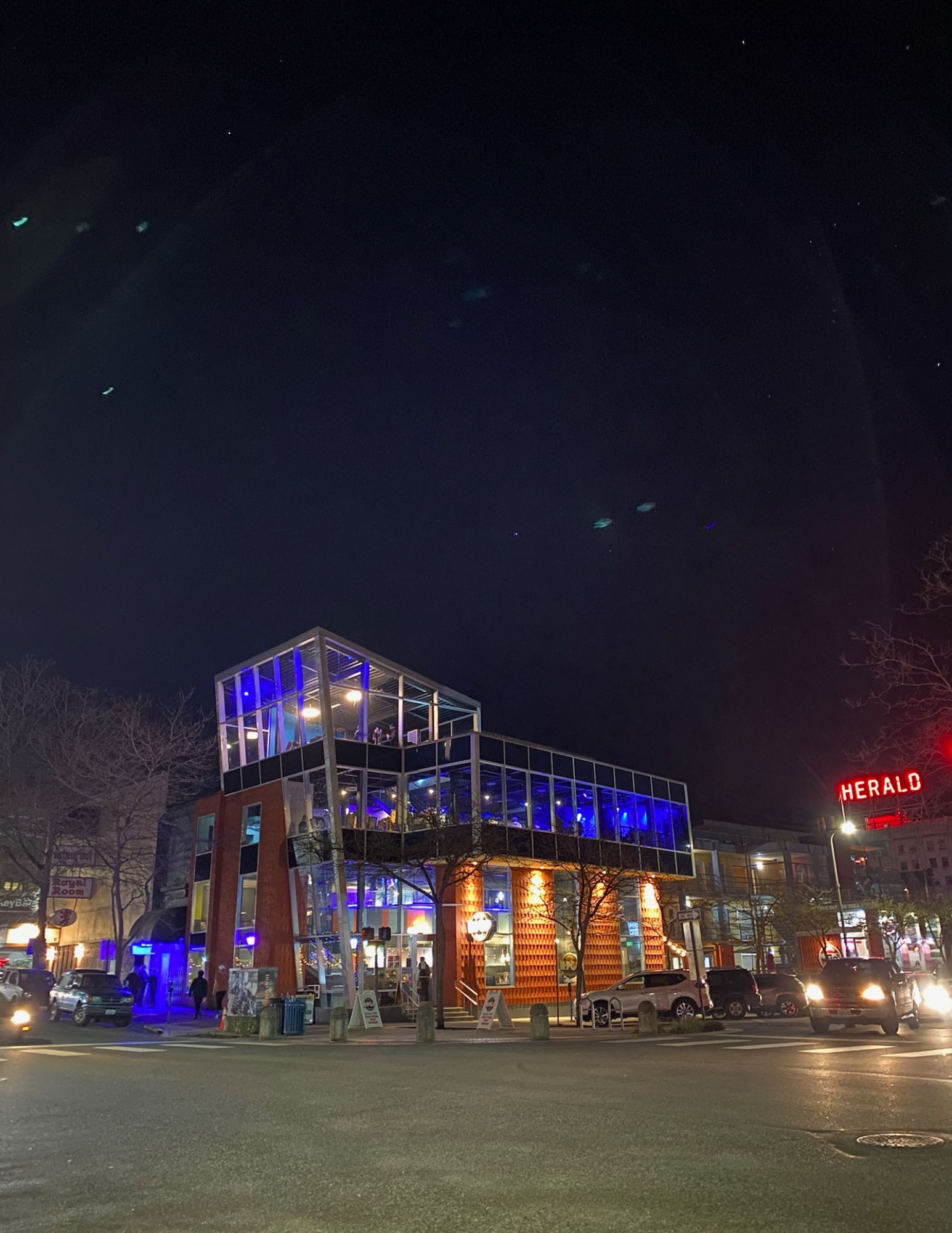 nighttime street scene featuring a windowed building emitting blue light