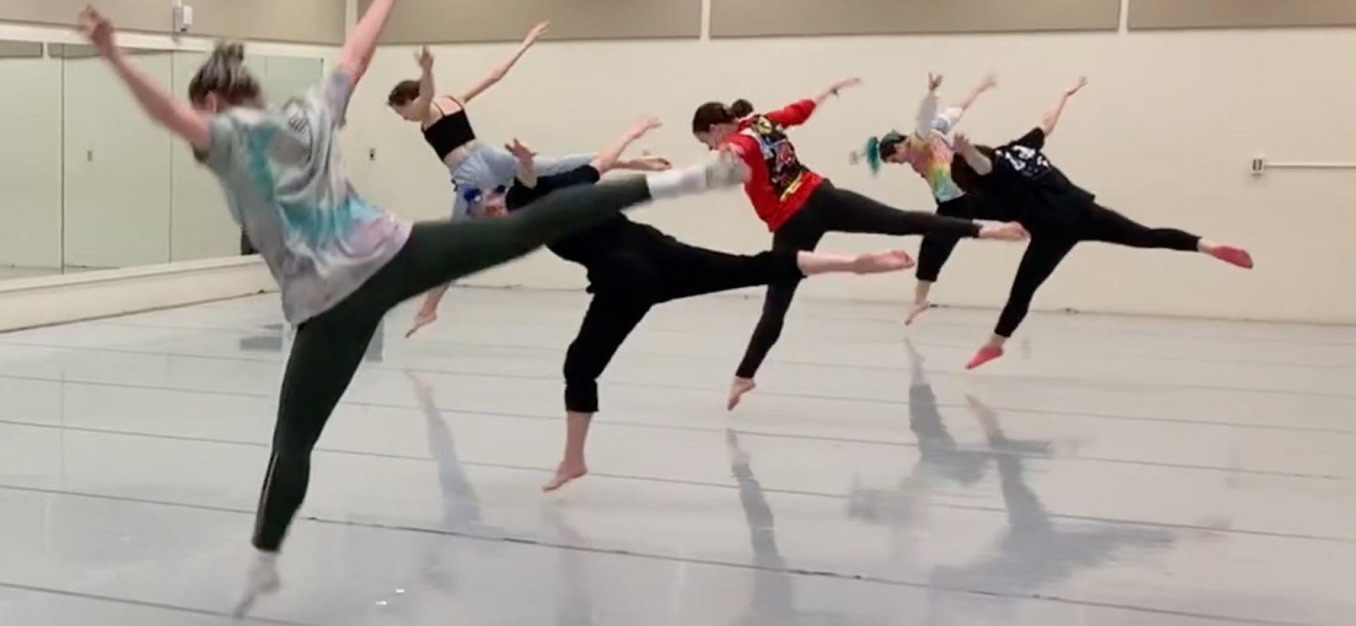 four dancers in a line, back legs extended, leaping forward away from the viewer