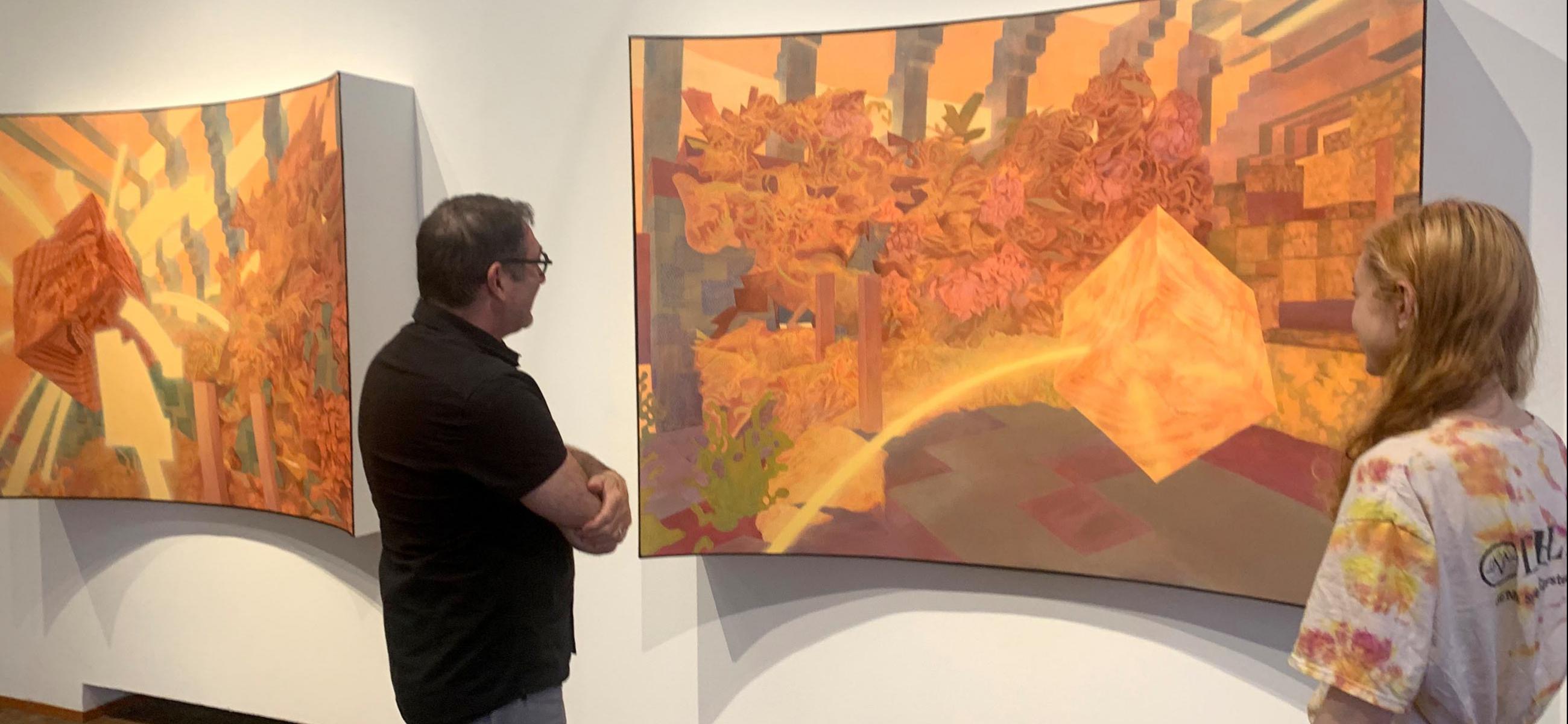 people looking at a large orange artwork in a gallery