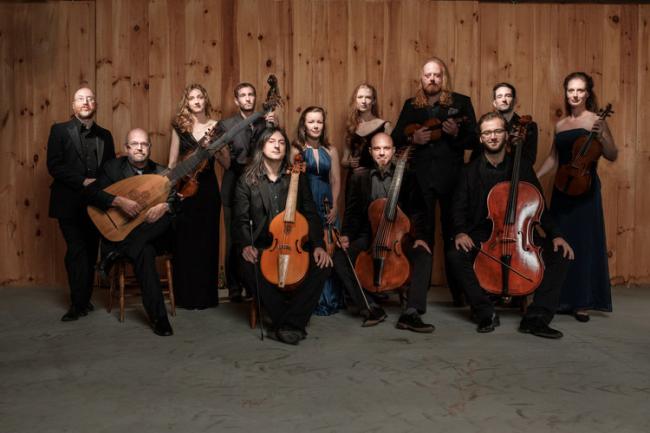 12 people dressed formally, posing with cellos, violins and similar instruments