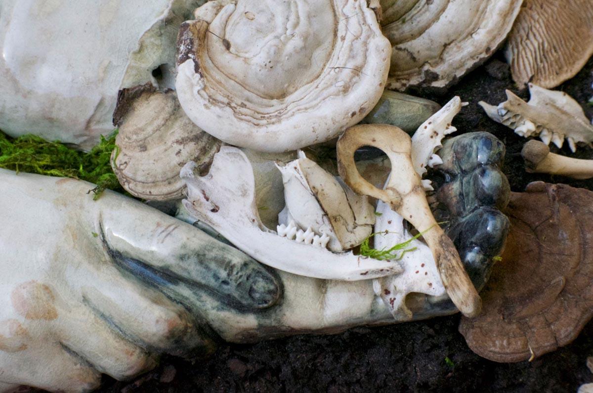 shells and bones mounded around pale white ceramic fingers and toes, the tips of which are blue-black.