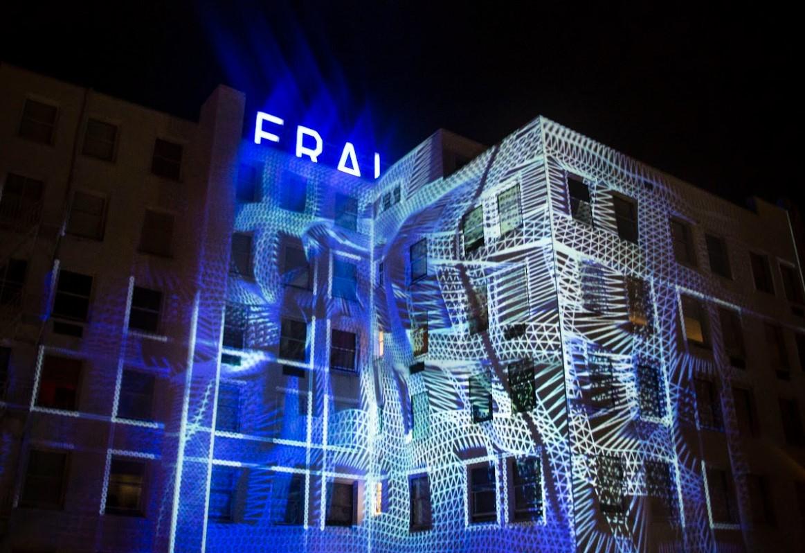 A warped grid of lines projected onto the Herald building, creating an illusion of the building being squeezed in the middle