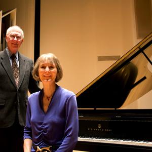 An elderly man and woman next to a Steinway piano
