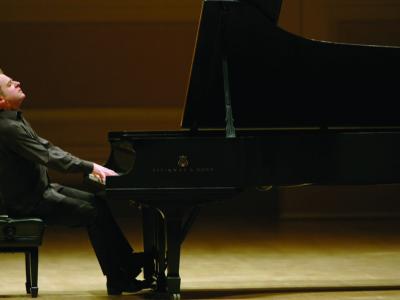 Jeremy Denk leans back and lifts his nose in the air with eyes closed as he plays on a Steinway piano